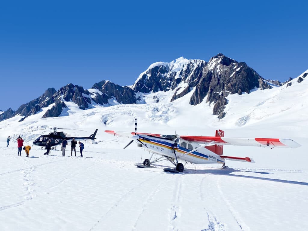 Passengers with helicopter and snow plane on snowfield