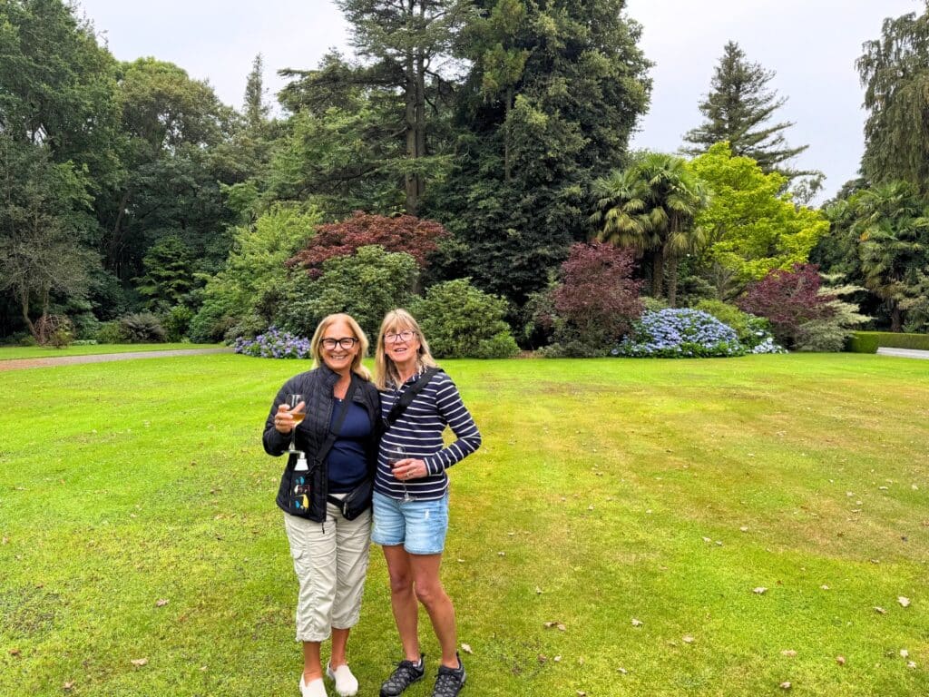 Two female travellers enjoying a glass of wine in the garden at Akaunui homestead, Canterbury, New Zealand