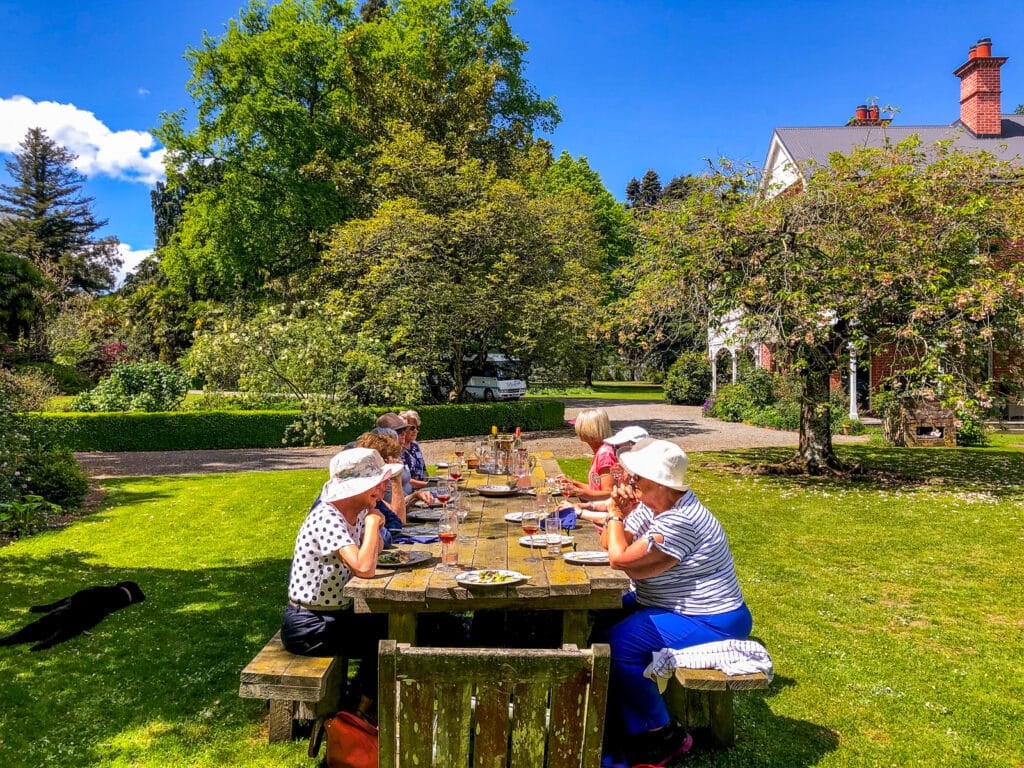 A small group of travellers enjoying lunch in the garden at Akaunui homestead, Canterbury, New Zealand