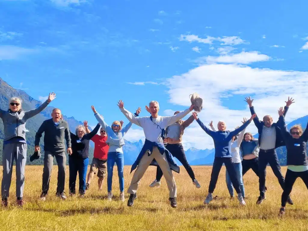 A group of senior travellers jumping for a photo on the Milford Road, New Zealand