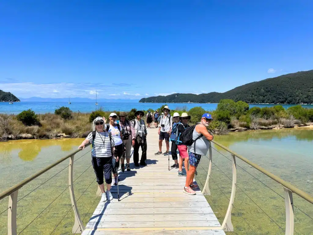 A group of senior travellers on the bridge at Awaroa Inlet, Abel Tasman National Park, New Zealand