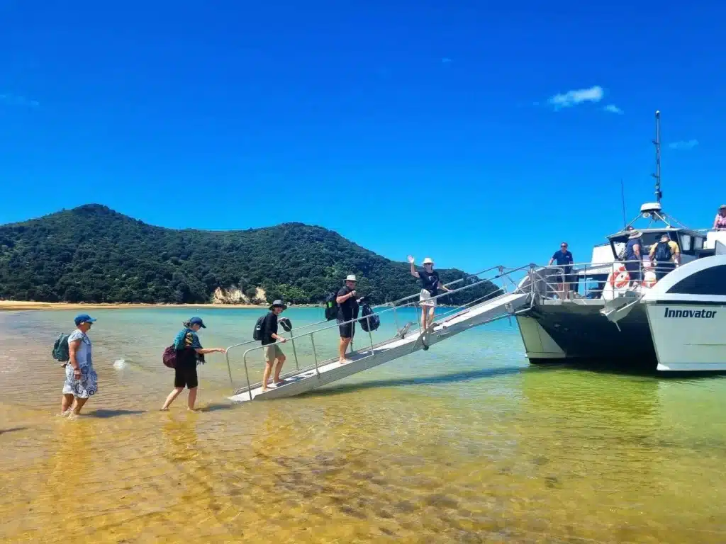 A small group of over-50 travellers boarding a water taxi in Abel Tasman National Park, New Zealand