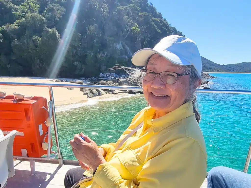 Senior traveller sitting on the deck during a cruise at Abel Tasman National Park, New Zealand