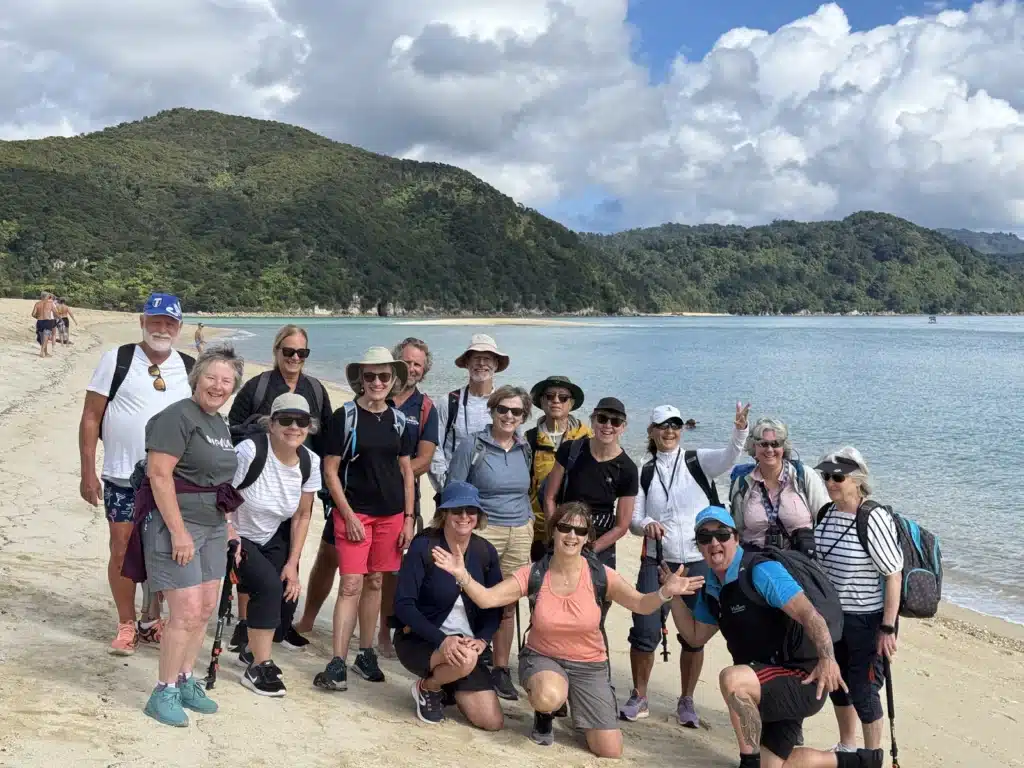 A group of over-50 travellers with their guides on the beach in Abel Tasman