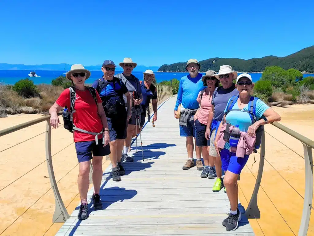 A group of senior travellers on the bridge at Awaroa Inlet, Abel Tasman National Park, New Zealand.