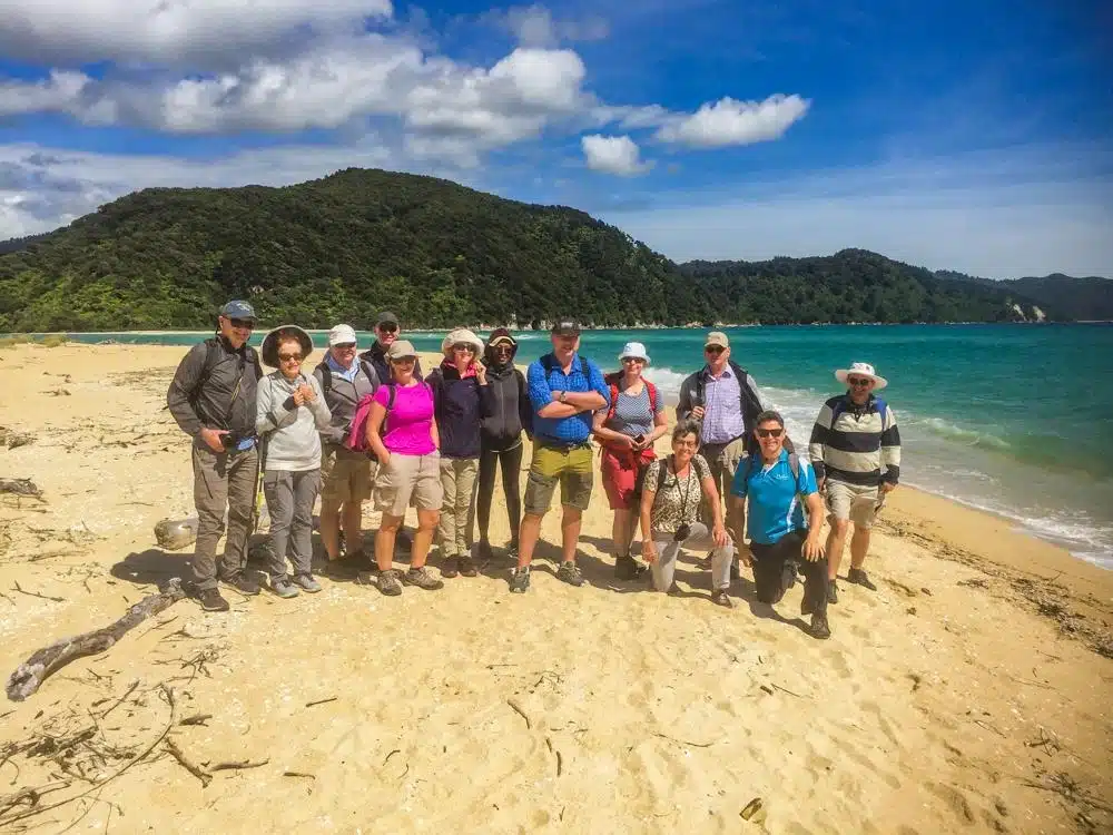 An senior travel group with their guide on the beach in Abel Tasman National Park, New Zealand