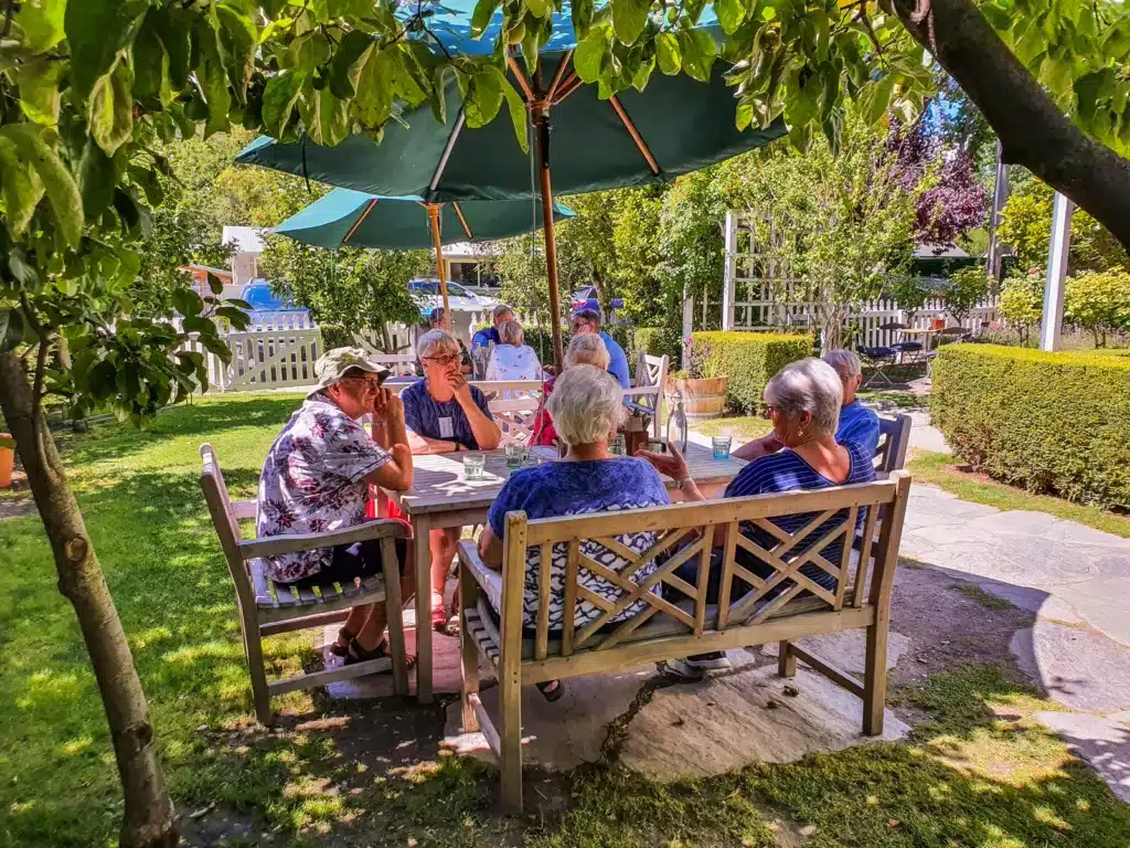 A group of senior travellers enjoying lunch in a garden cafe in Arrowtown, near Queenstown, New Zealand