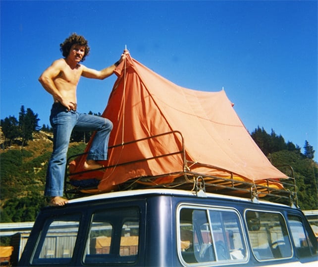 Guide posing with tent on top of MoaTrek van circa 1970s